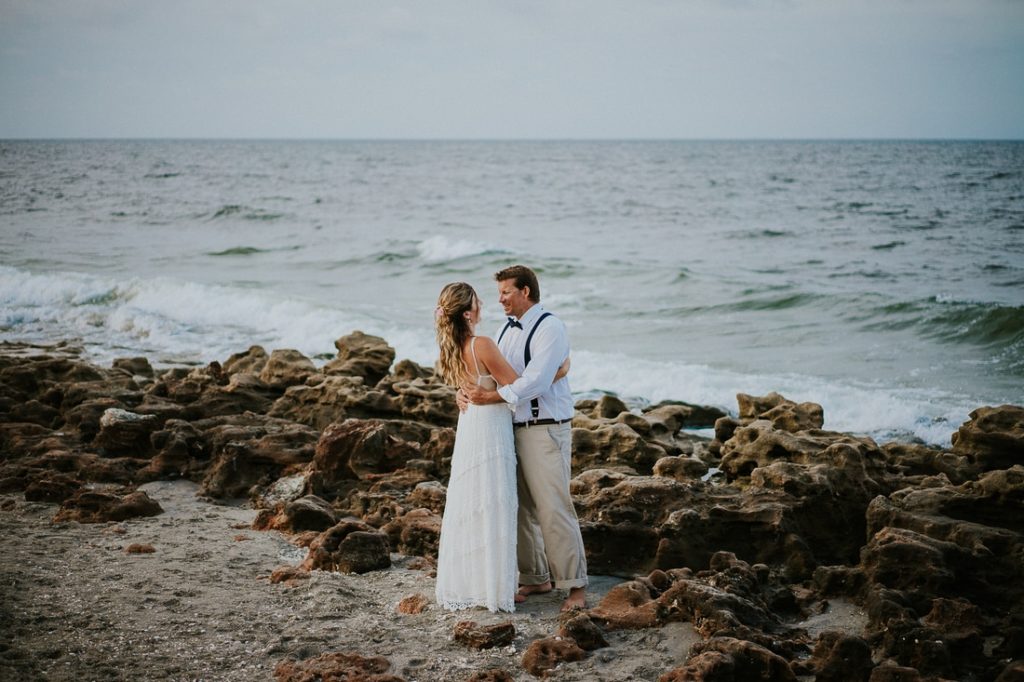 Coral Cove beach elopement wedding couple embrace and smile on rocky beach