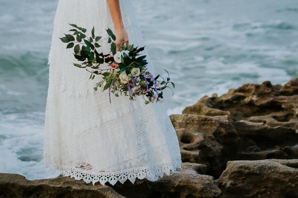 Coral Cove beach elopement bride in white lace beach wedding dress holding bouquet close-up