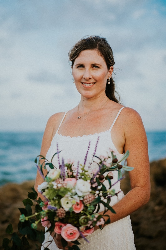 Coral Cove beach elopement bridal portrait in white lace beach wedding dress holding bouquet close-up