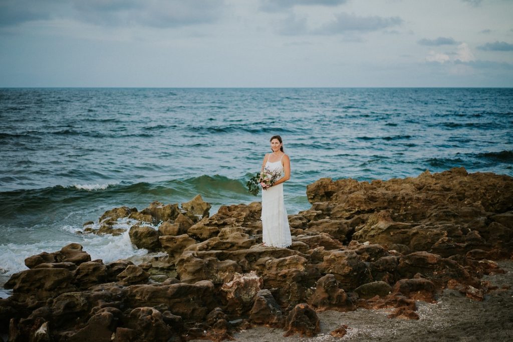 Coral Cove beach elopement with bride standing on rocky beach with ocean behind her