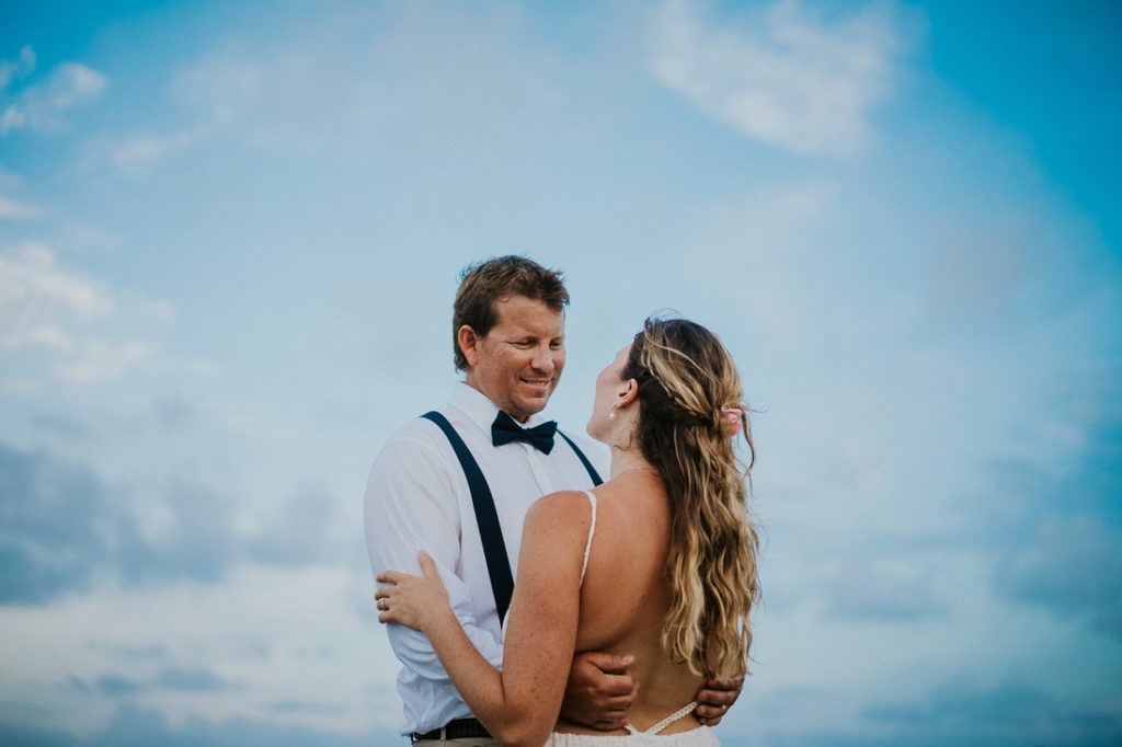 Coral Cove beach elopement wedding couple look at each other under blue cloudy sky