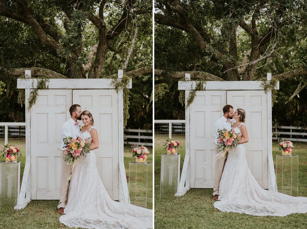 Bride and Groom first kiss in front of ceremony wedding door under oak tree at Pink Lemonade photoshoot Twisted Oak Farm Vero Beach FL barn wedding