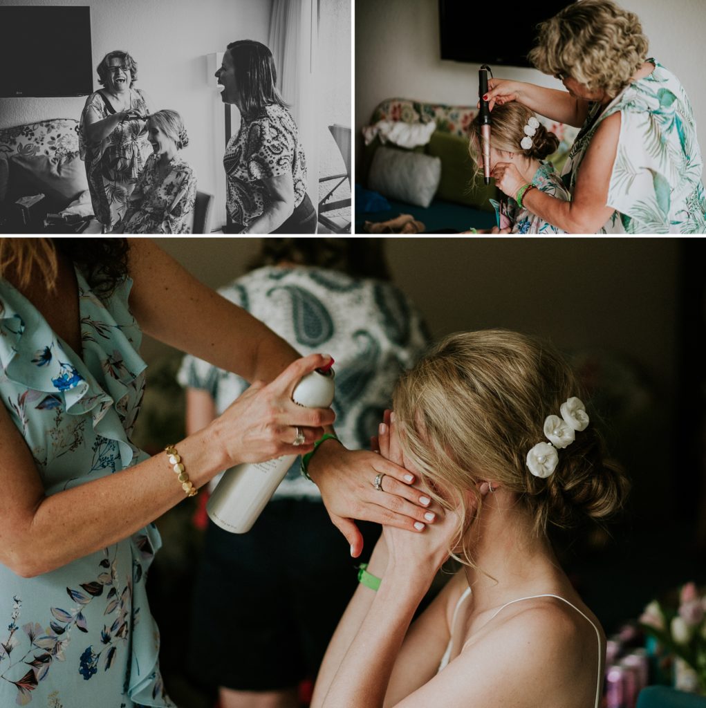 Bride's family curling her hair and spraying hair spray while bride covers her face with her hands