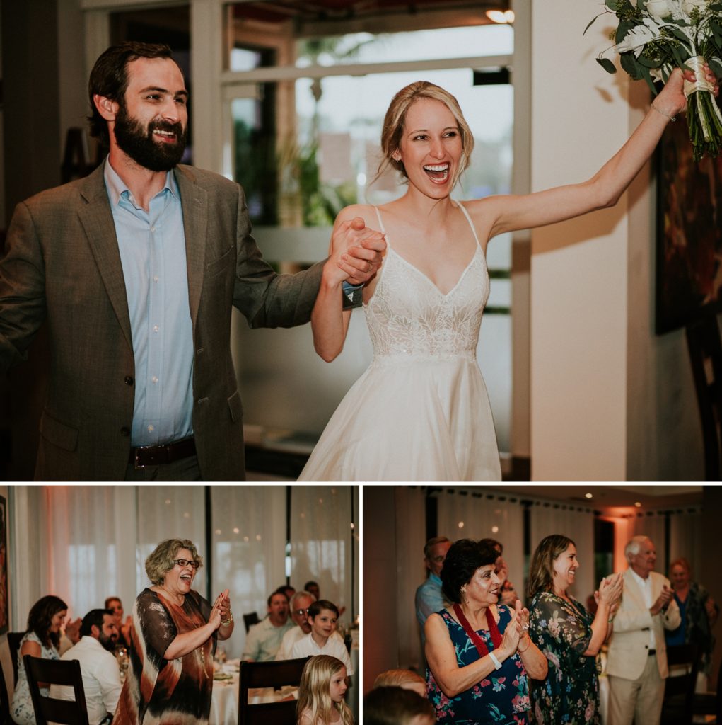 Bride and groom excitedly enter the reception as their family stands and claps