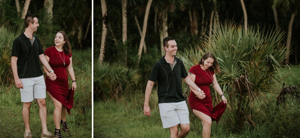 Woman in red dress walks with fiancé and laughs during engagement session at Myakka river state park