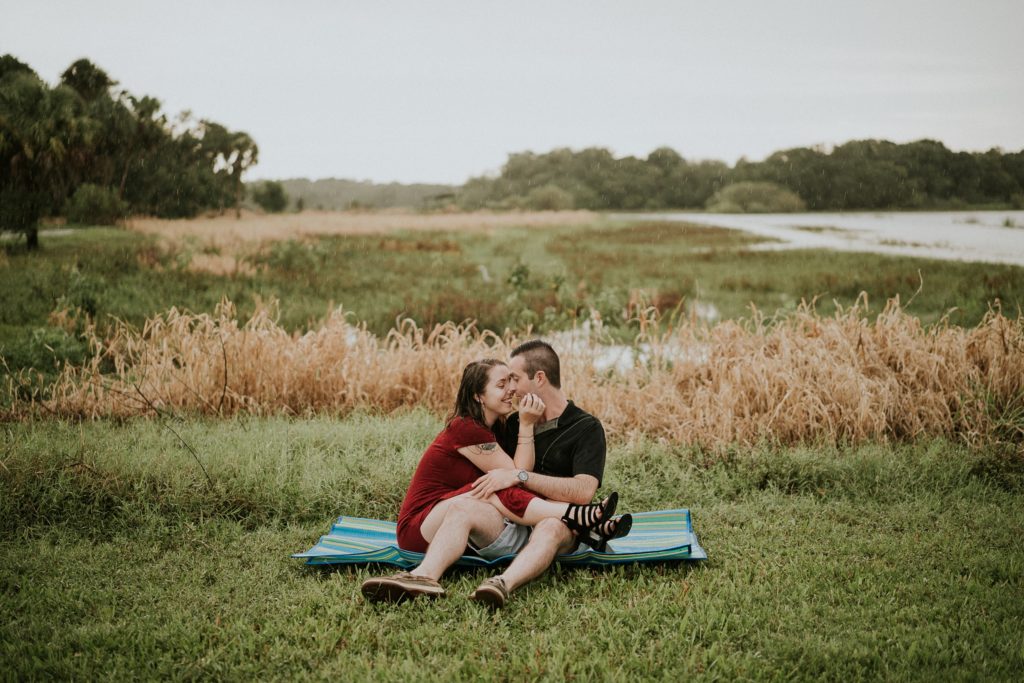 Engaged couple sitting on picnic mat in the grass at Myakka river state park