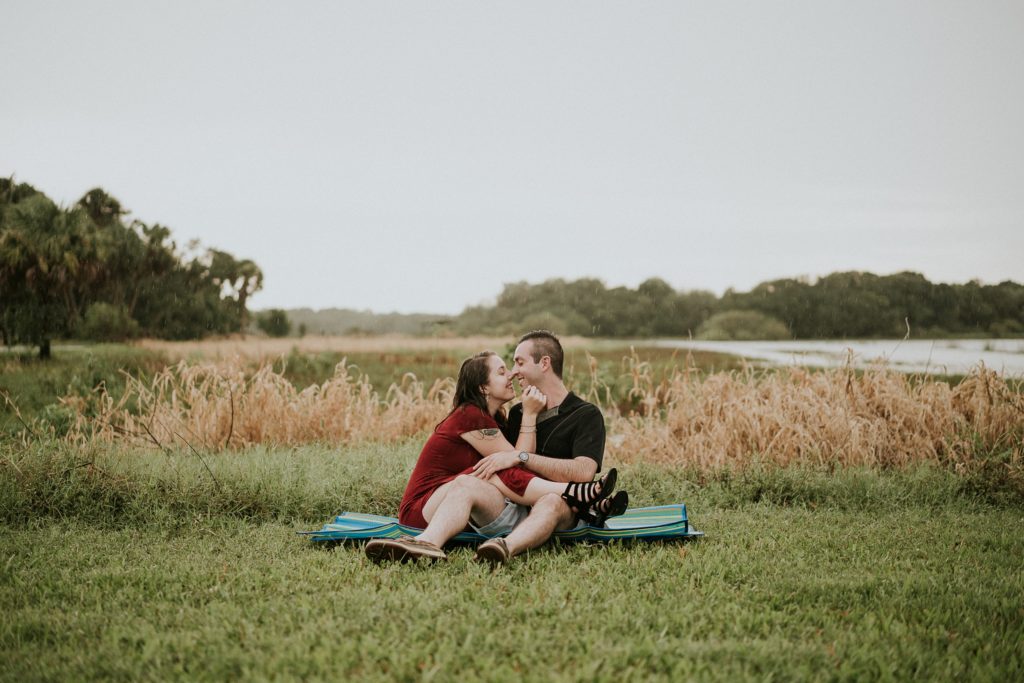 Engagement photos of couple sitting on picnic mat in the grass at Myakka river state park before Sarasota wedding