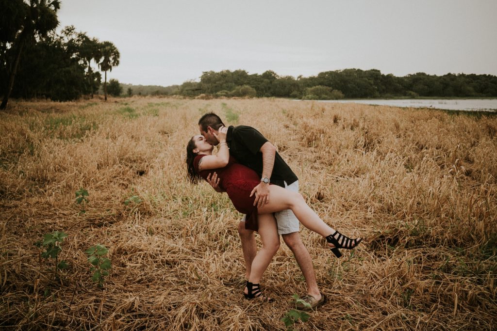 Sarasota wedding couple dip kiss in golden field at Myakka River state park for engagement photos