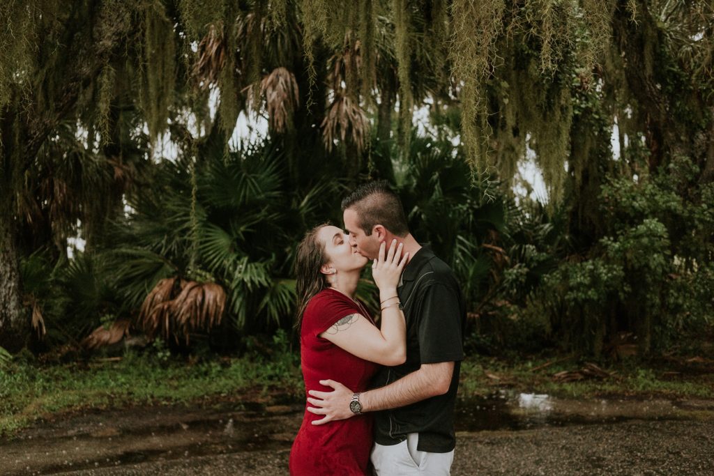 Sarasota wedding couple kissing in the rain at Myakka River state park for engagement photos under Spanish moss