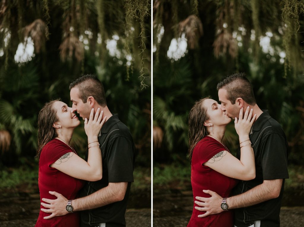 Woman holds man's cheek and they kiss in the rain for engagement photos at Myakka River state park before Sarasota wedding