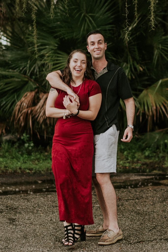 Sarasota wedding couple in red dress hold hands and pose in Myakka River state park for engagement photos