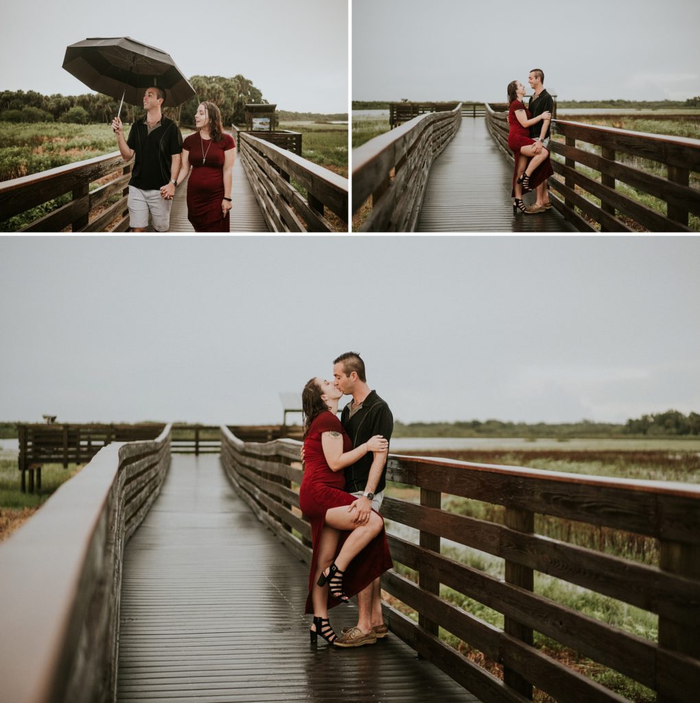 Engaged couple holding umbrella walking on Myakka birdwalk and kissing