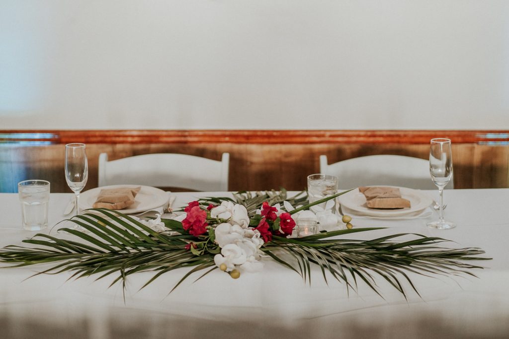 Coastal theme wedding sweetheart reception table with palm fronds and tropical floewers