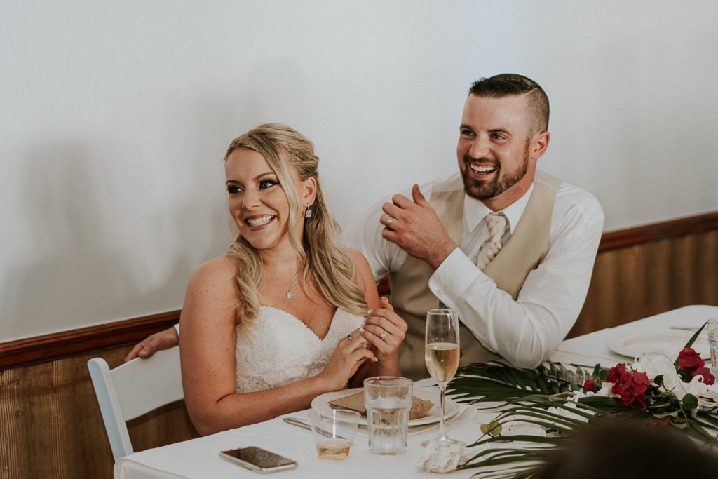 Wedding couple smiles and laughs during bridesmaid speech at their small Florida destination wedding