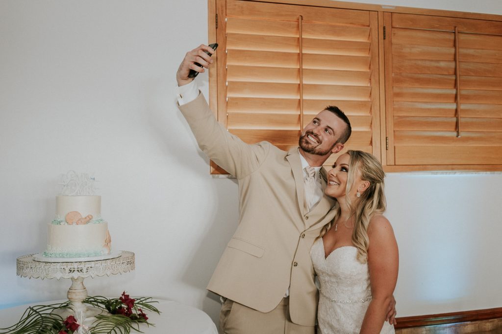 Bride and groom take a selfie in front of their wedding cake at Sailfish Marina Resort reception