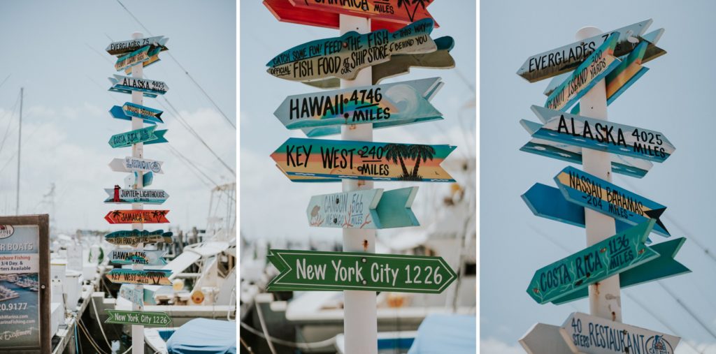 Decorative painted directional signs featuring different cities and how many miles they are from West Palm Beach