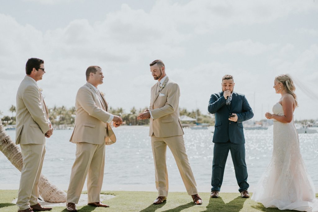 Best man hands the groom wedding rings and the groomsmen wear khaki suits