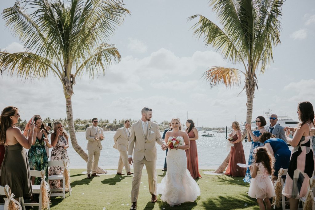 Bride and groom walk down aisle with palm trees at Sailfish marina Singer Island FL destination wedding