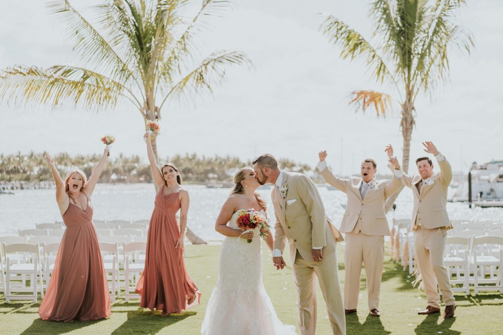 Bride and groom kiss as wedding party cheers at Sailfish Marina Singer Island destination wedding in West Palm Beach Florida