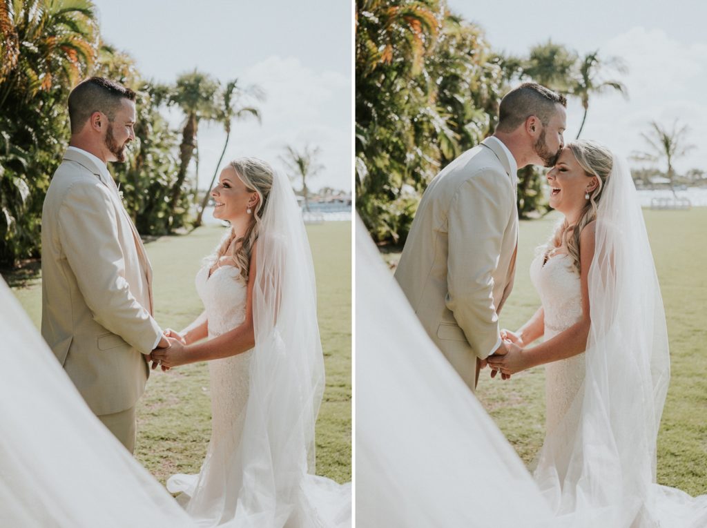 Bride and groom hold hands and kiss forehead with long wedding veil toss in front of them at Singer Island wedding