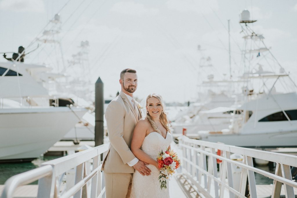 Bride and groom smile on Sailfish Marina yacht docks in West Palm Beach for Florida destination wedding on Singer Island