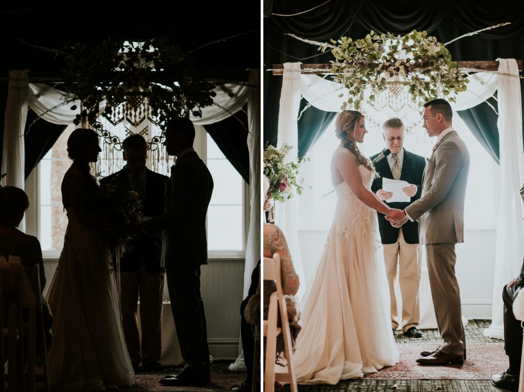 Silhouette and backlit view of bride, officiant, and groom at indoor wedding ceremony