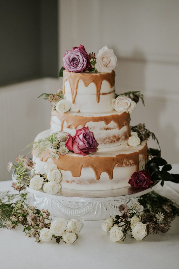 Naked wedding cake with purple and white roses