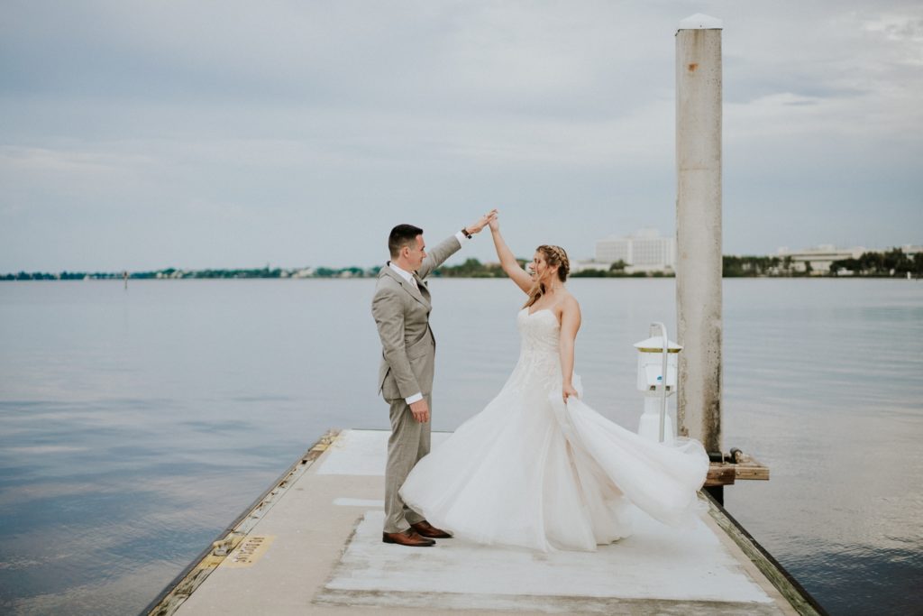 Downtown Stuart FL elopement couple dances on boat dock on St. Lucie River with cloudy sky