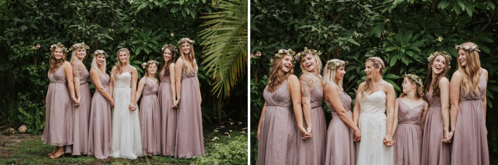 Bride and her bridesmaids in lilac dresses and flower crowns hold hands and smile at each other