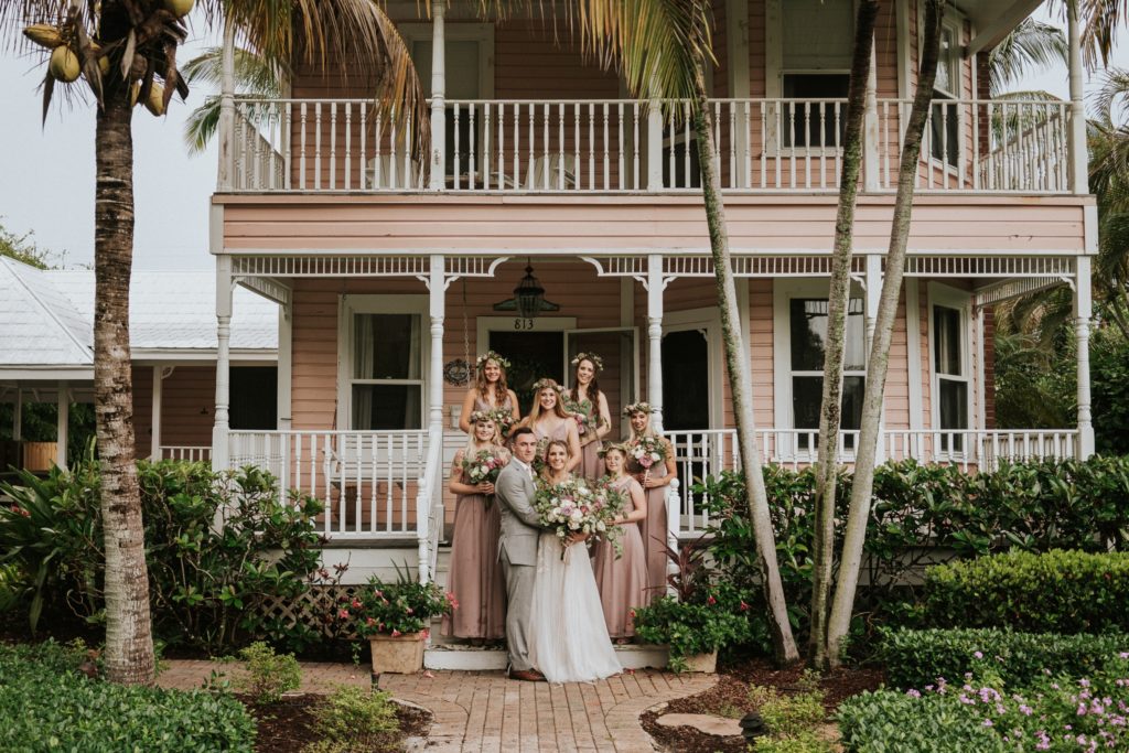 Wedding couple with bridesmaids in front of Downtown Stuart historic pink home