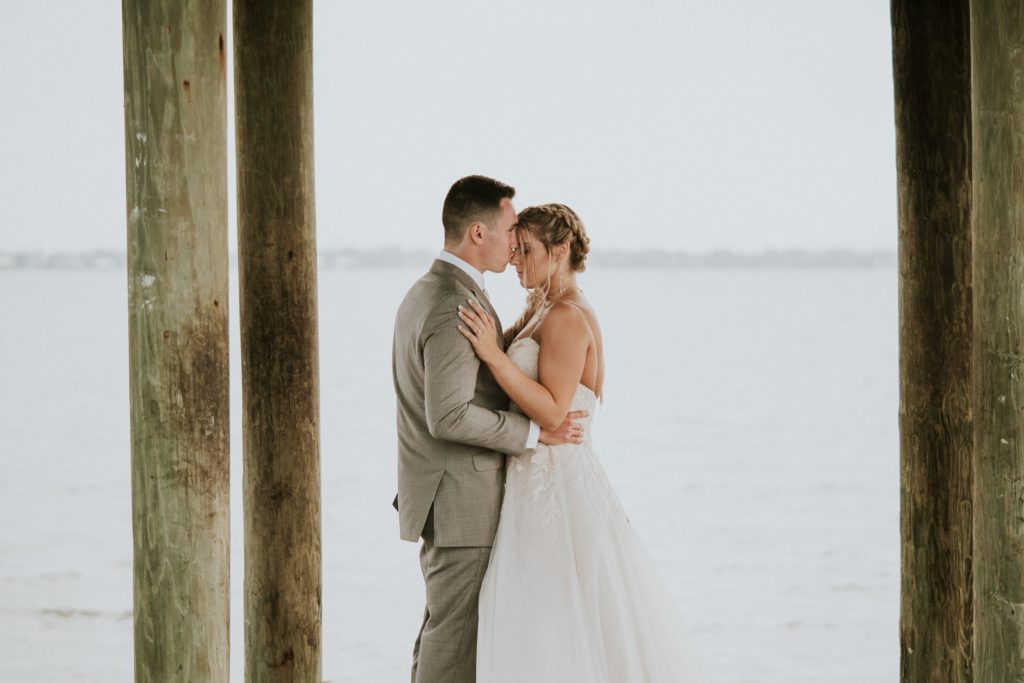 Groom kisses brides forehead on the dock on the water at Hutchinson Island weddig