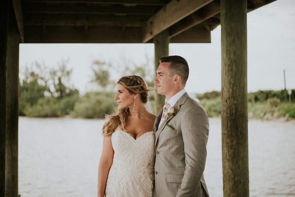 Bride and groom look out on the water from the covered dock on Hutchinson Island on their wedding