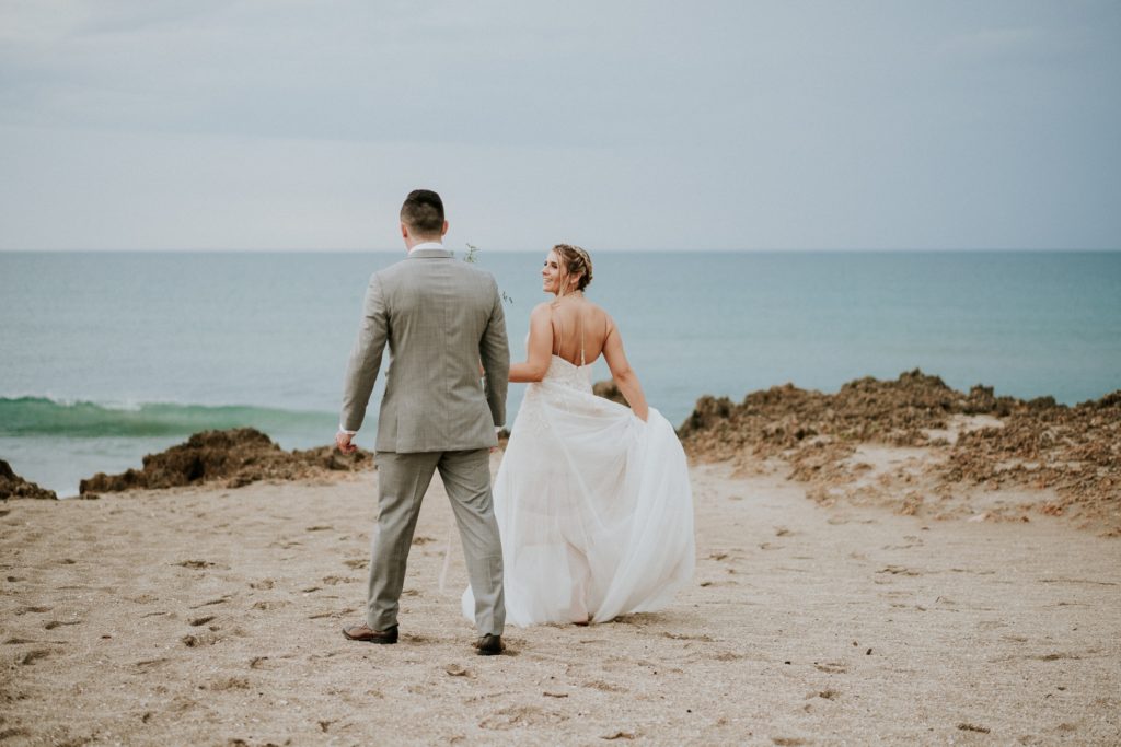 Bride and groom walk on the beach to the water for House of Refuge elopement