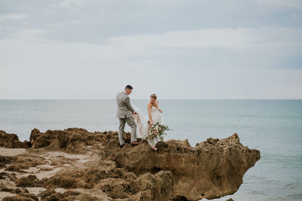 Groom helps bride climb limestone at House of Refuge elopement