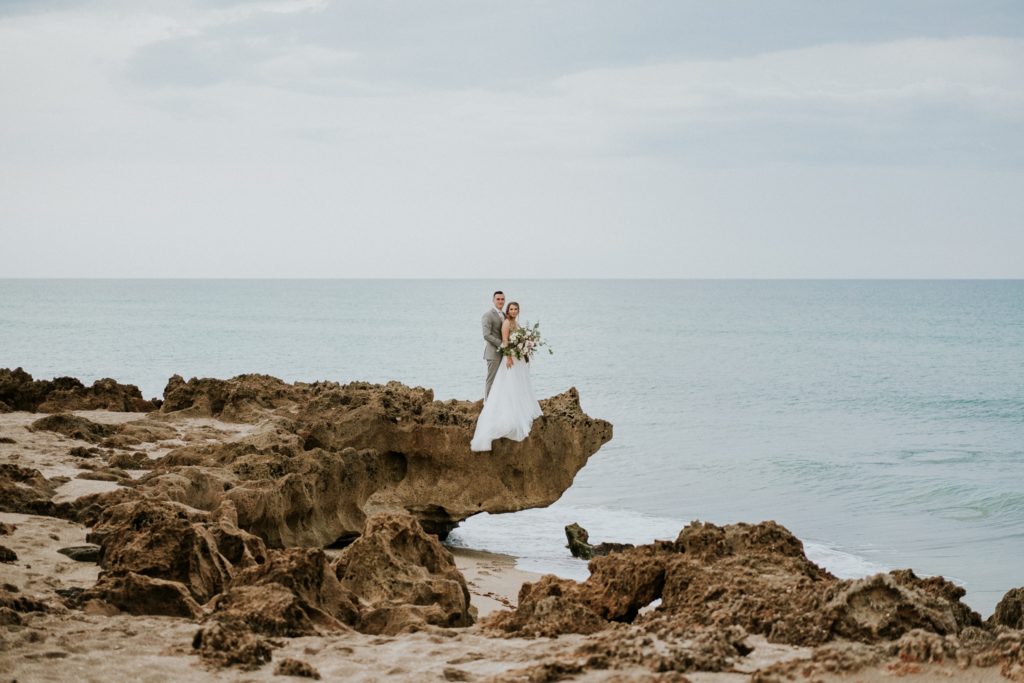 Wide angle view of wedding couple eloping in Florida standing on limestone rock for House of Refuge elopement