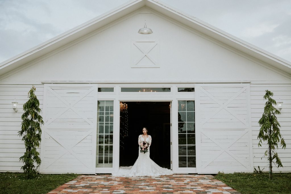 Bride stands in front of Ever After Farms Ranch Wedding Barn venue in Indiantown Florida