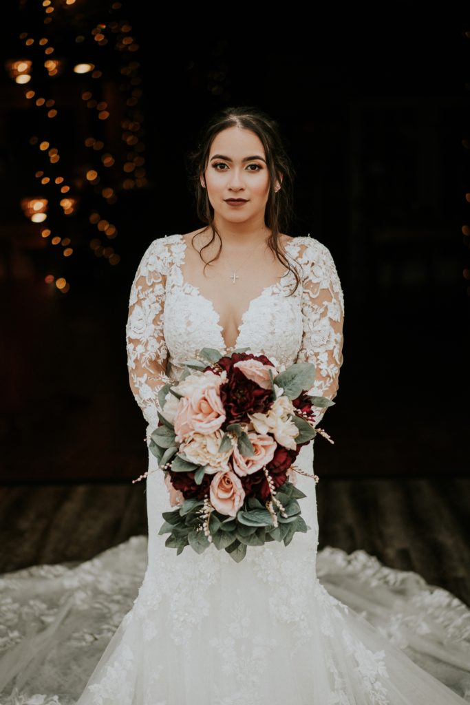 Bride wearing white lace floral Martina Liana wedding gown holds pink and red rose flower bouquet
