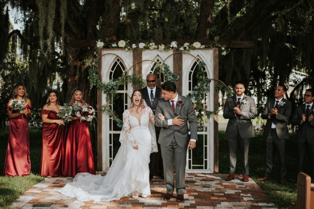 Newlyweds walk down aisle in front of white window wedding altar ceremony backdrop at Ever After Farms Ranch