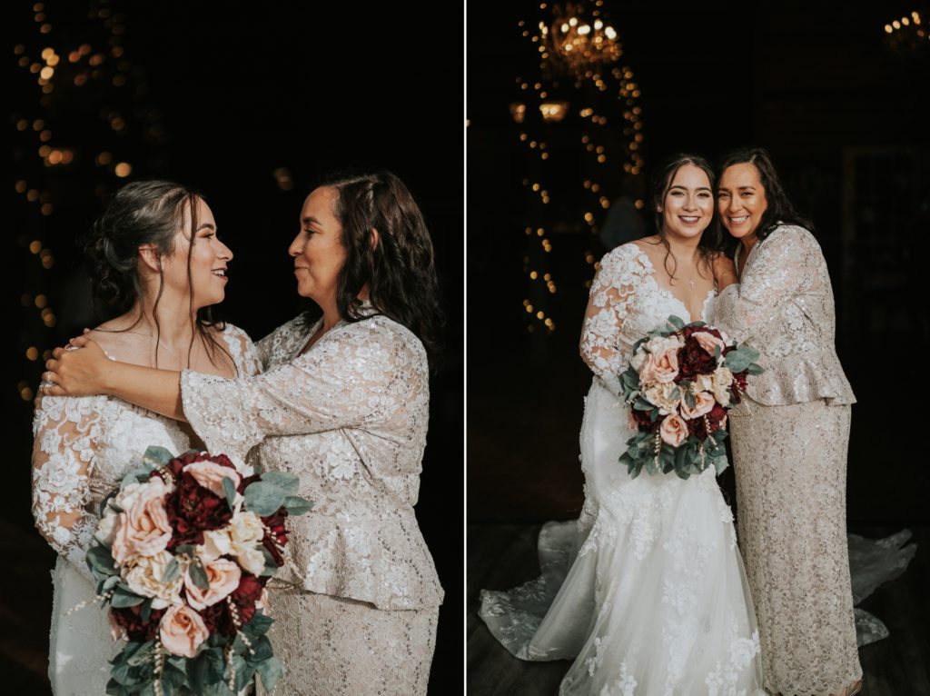 Bride holding bouquet with red and pink flowers hugs mom in grey lace dress
