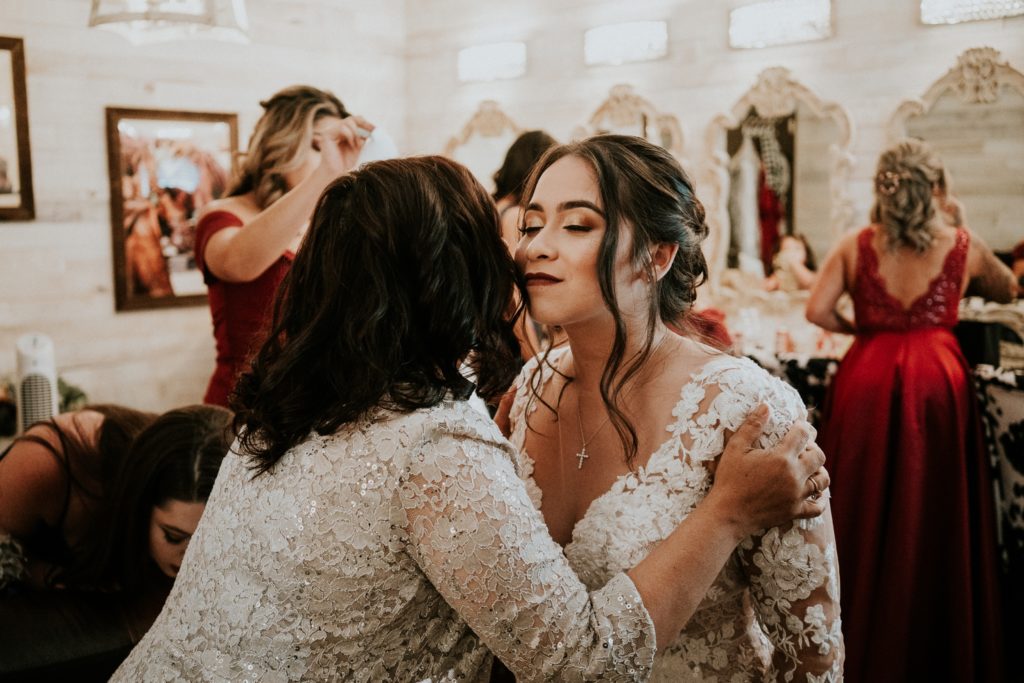 Mom kisses bride on the cheek in bridal suite