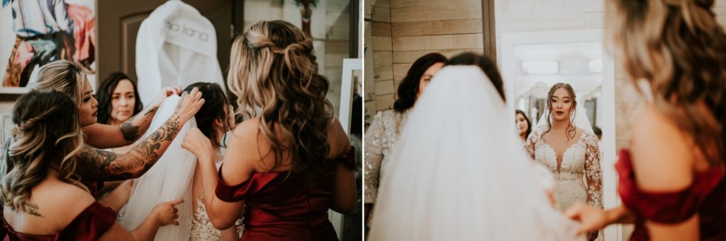 Bridesmaids help put wedding veil on bride as she looks at herself in mirror