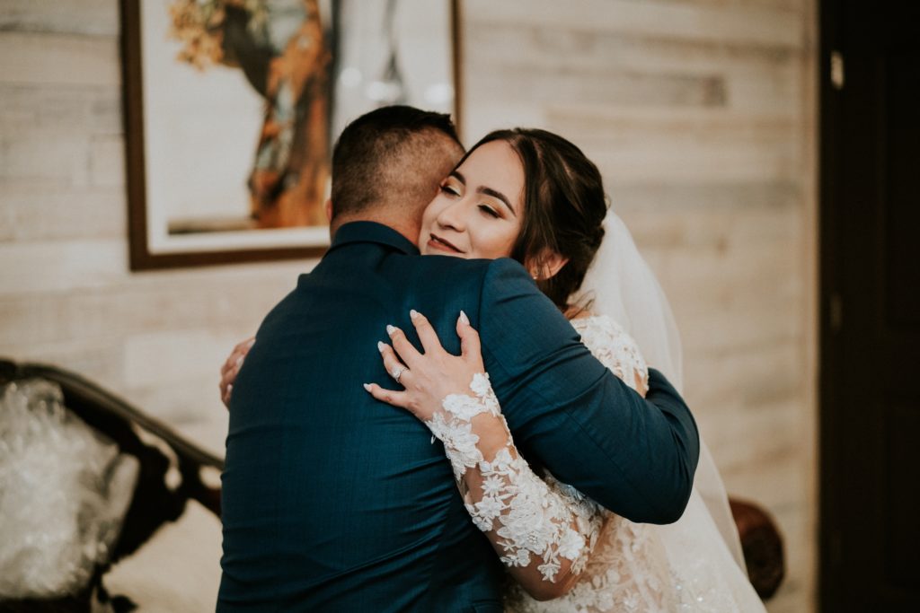 Step-dad hugs bride in bridal suite