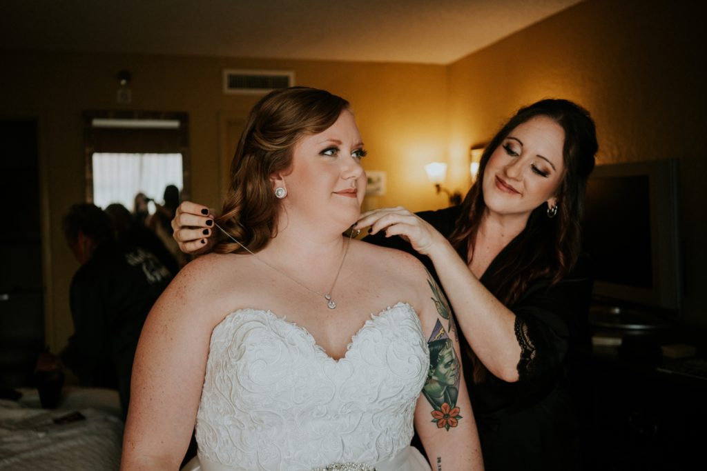 Bridesmaid puts on bride's necklace after putting on dress revealing Frankenstein arm tattoo