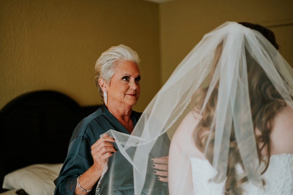Mother of the bride adjusts daughter's veil and looks lovingly at her