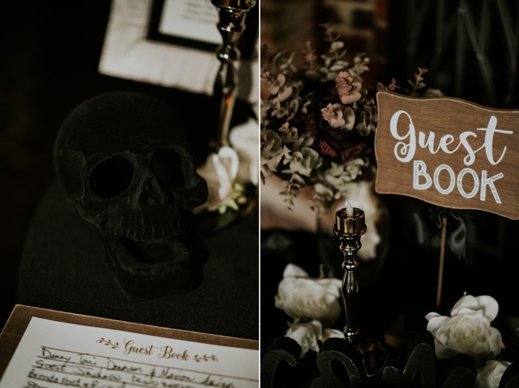 Close up of black velvet skull wedding decor and wood guest book sign with pewter candlestick