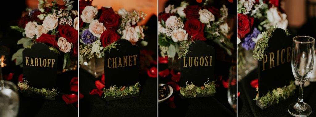 The names of actors and directors of horror movies (Karloff, Chaney, Lugosi, and Price) written in gold on black headstone wedding centerpiece decor with red and pink roses