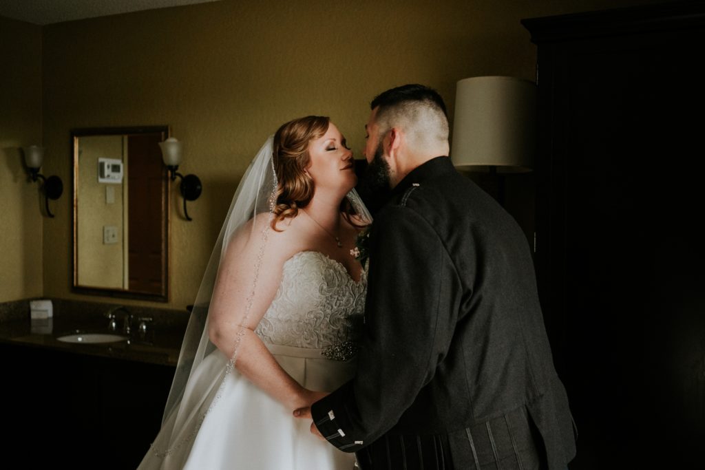 Bride and groom kiss in hotel room during first look