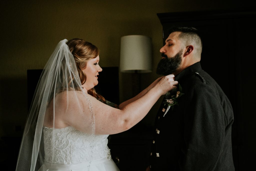 Bride fixes groom's bowtie in hotel room