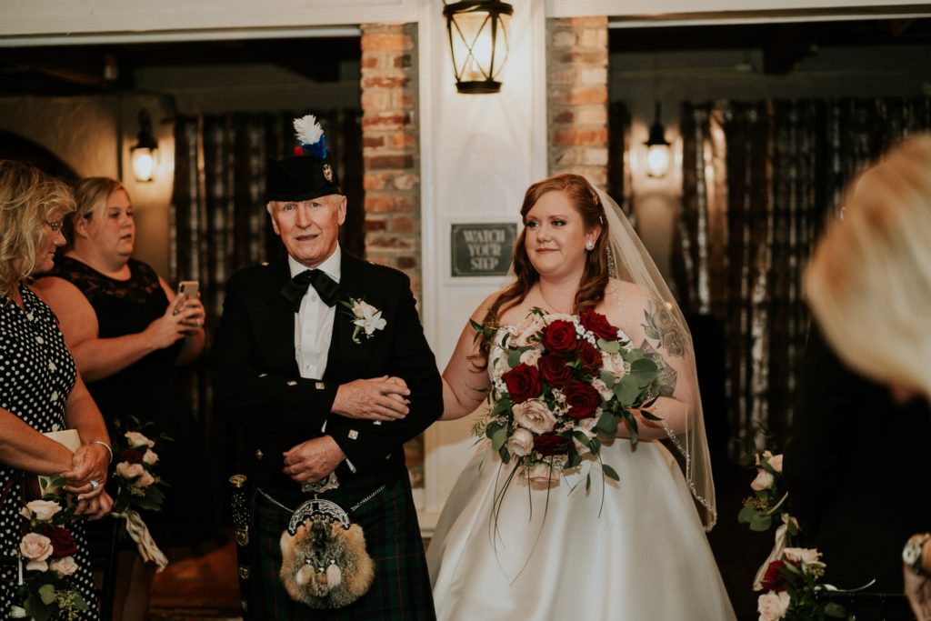 Father wearing traditional Scottish attire and kilt walks his daughter, the bride, down the aisle at Historic Maxwell Room indoor wedding ceremony