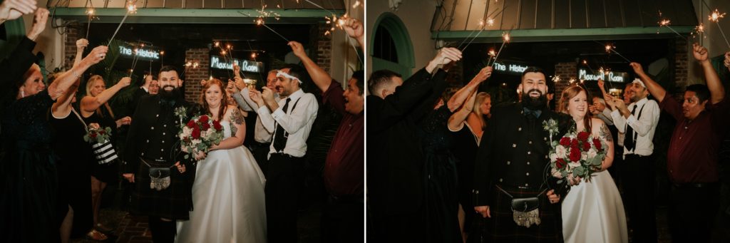 Newlywed groom and bride laughing with guests as they exit the Historic Maxwell Room during a sparkler exit at night